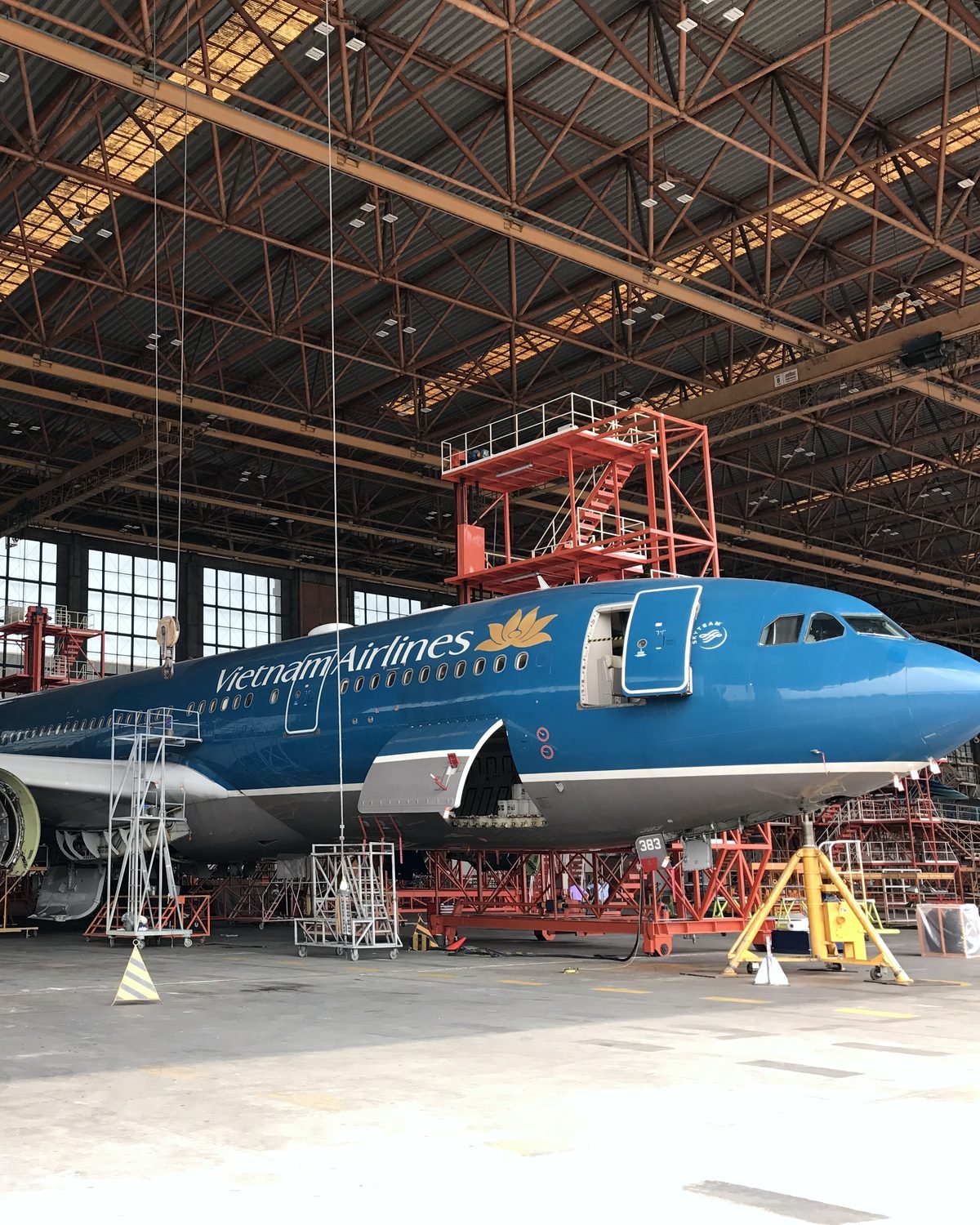 Vietnam Airlines widebody in the hangar for heavy maintenance, access staging around the nose